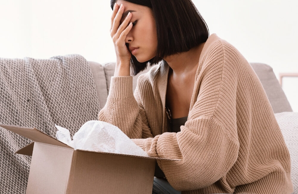 Mulher decepcionada diante de uma caixa aberta